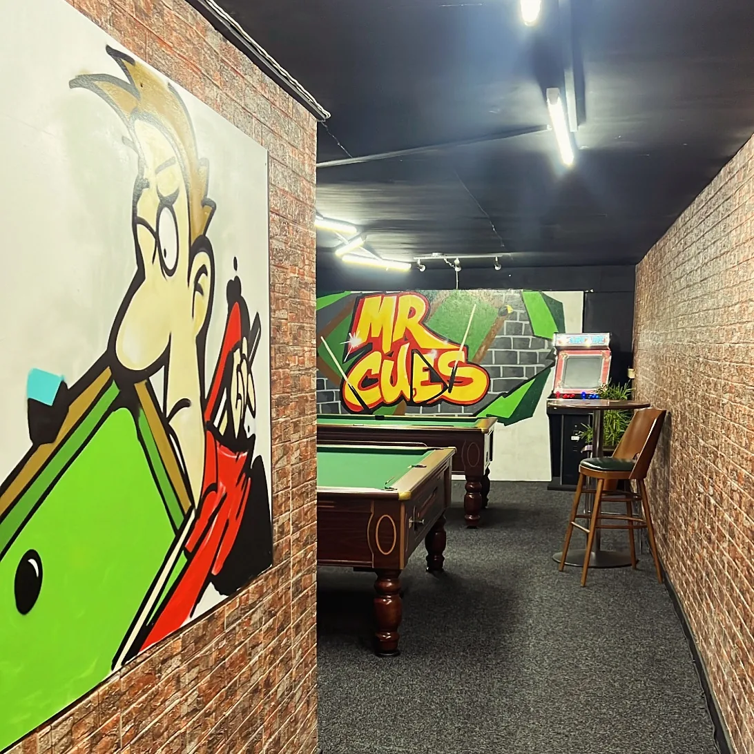 Pool tables and colorful mural inside Mr Cue’s Pool Bar